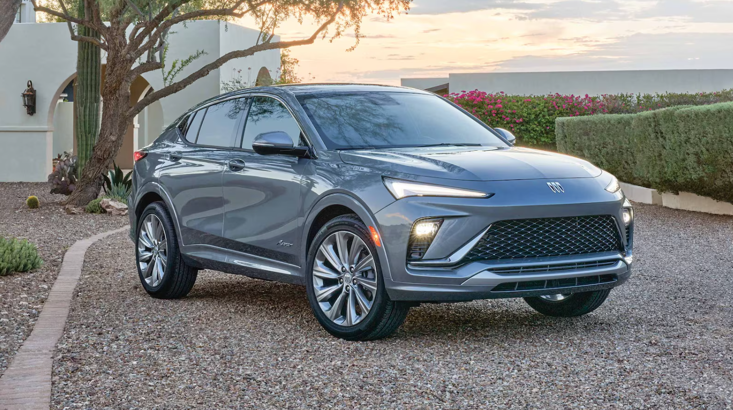 A gray 2026 Buick Envista parked in a landscaped residential driveway at sunset.